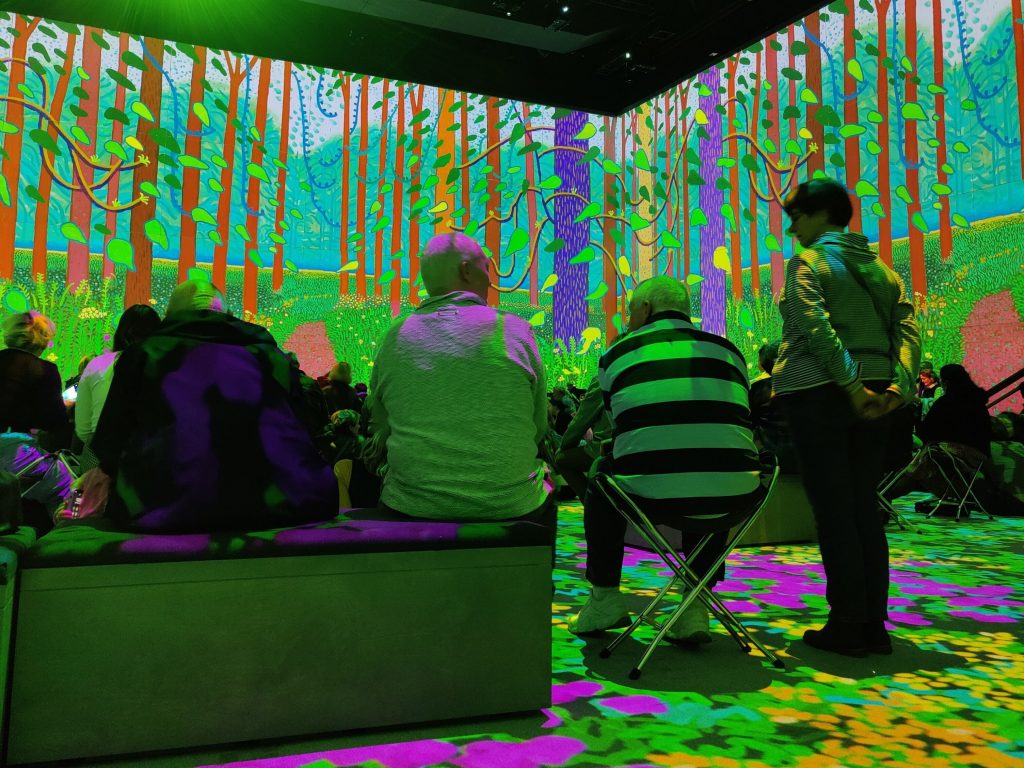 Immersive David Hockney exhibition at Lightroom with animated images projected across walls.