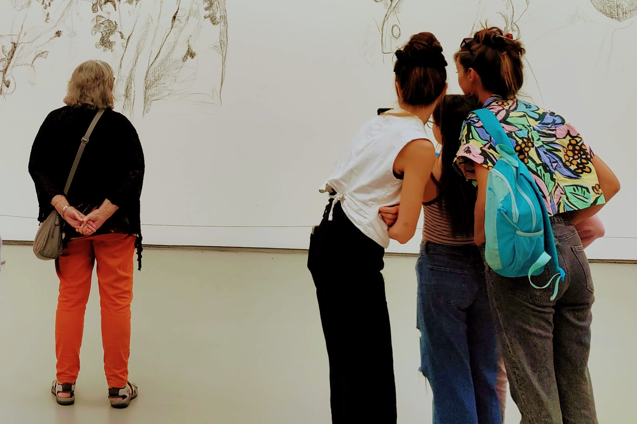 Group of three people and one single person looking at an artwork displayed on a gallery wall.